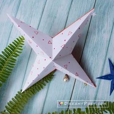 an origami star is sitting next to some ferns