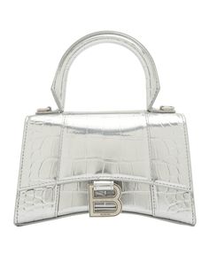 Balenciaga satchel in metallic crocodile-embossed calfskin. Rolled top handle. Removable, adjustable shoulder strap; 18.5"/47cm - 46"/117cm drop Flap top with hanging "B" hardware; snap closure. Exterior, slip compartment at back. Interior, one slip pocket. Approx. dimensions: 5.5"H x 7.5"W x 4"D/ 14cmH x 19cmW x 10cmD Made in Italy. Balenciaga Hourglass Bag, Balenciaga Top, B Logo, Black Balenciaga, Embossed Bag, Balenciaga Bag, Leather Silver, Satchel Handbags, Satchel Bag