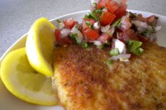 a plate topped with fish and vegetables next to a lemon wedge