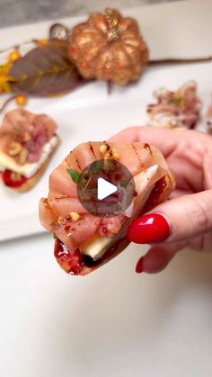 a person holding up a piece of food in their hand with other foods on the table behind them