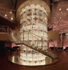 a spiral staircase in the middle of a room with glass bottles on it's walls