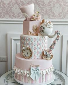 a three tiered cake decorated with pink and white designs, including a teapot