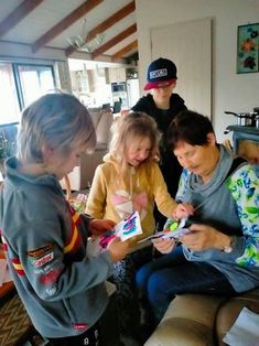 a group of people sitting around each other in a living room playing with cell phones