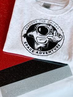 Astronaut Spaceman Planets Shirt, Funny Space Tee, Planets Galaxy Fans Birthday Gift Tshirt, Space Stars Shirt, Moon Tee, Explore The Galaxy Shirt, Space Adventure Shirt, Glittered Logo Shirt ZaliArt products are made with premium quality materials and designed to help you look and feel your best! Please look over the product images to see the color variations available for each style. The main image features the unisex tee in white with a black space monogram. - Unisex Tee: Soft and lightweight 1st Birthday Onesie, Space Tee, Funny Toddler Shirt, Galaxy Shirt, Adventure Logo, Animal Party Theme, Cousin Gifts, Space Adventure, 1st Birthday Shirts