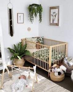 a baby crib in a white room with potted plants and other decorations on the wall