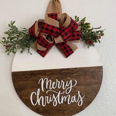 a wooden sign that says merry christmas with a bow on it and evergreen branches hanging from the front