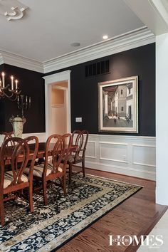 a formal dining room with black walls and white wainscoting on the wall