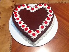 a heart shaped cake on a white plate with red and white decorations in the shape of a heart