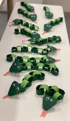 some very cute looking paper crafts on a white table with green and red items in the shape of snakes