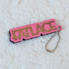 a pink and gold tag with the word fatace on it sitting on a white surface