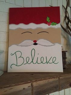 a canvas with santa claus's face and the word believe on it is sitting on a shelf