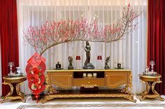 a table with vases and decorations on it in front of a red drapes