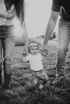 a black and white photo of a toddler holding the hand of an adult's hand