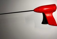 a red and black object hanging on the side of a white wall with a black handle