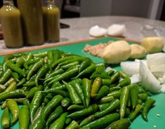 green beans, onions and garlic on a cutting board next to bottles of olive oil