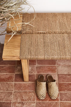 a pair of shoes sitting on top of a wooden bench next to a potted plant