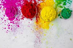 three bowls filled with different colored powders on top of a white table next to each other