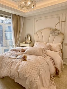 a bedroom with a bed, chandelier and window overlooking the cityscape