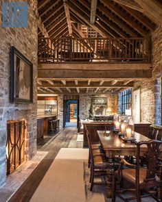 a large dining room with stone walls and wooden tables in front of an open fire place