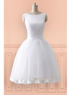 a short white dress on a mannequin stand in front of a pink wall