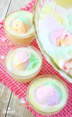 three desserts are sitting on a table with pink and green frosting in them