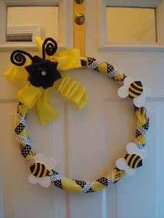 a yellow and black wreath on the front door with bees hanging from it's sides