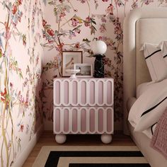 a bedroom with floral wallpaper and pink bedding, along with a white nightstand