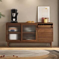 a coffee maker on top of a wooden cabinet next to a potted plant in a living room