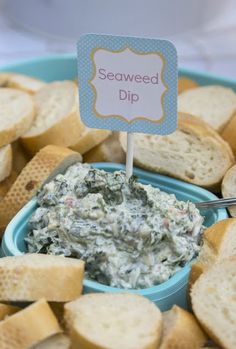 a blue bowl filled with dip surrounded by crackers on a white table cloth and a sign that says seaweed dip