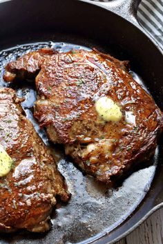 two steaks in a skillet with butter on the top and some sauce on the bottom