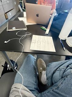 a person sitting at a table with an apple laptop and headphones in front of them