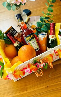 a basket filled with oranges and drinks on top of a wooden table