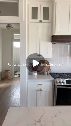 a kitchen with white cabinets and marble counter tops