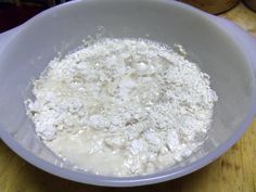 a white bowl filled with flour on top of a wooden table