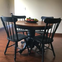 a bowl of fruit on top of a table next to two chairs and a bowl of fruit