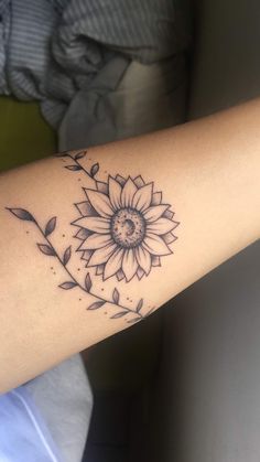 a woman's arm with a sunflower tattoo on the left side of her arm