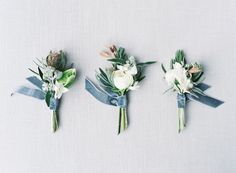 three boutonnieres with white flowers and greenery