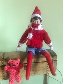 an elf doll sitting on top of a wooden box next to a teddy bear toy