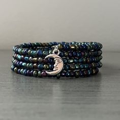 Celestial themed memory wire with seed bead bracelet is a great addition to your jewelry collection! Measures 7 inches around, but memory wire will expand beyond that. This is made with glass seed beads in blue, purple, and greens. Bracelet includes a silver plated crescent moon charm. Memory wire is strong, flexible, and adjustable to most wrist sizes. It gives the appearance of several stacked bracelets.  This bracelet would make a wonderful gift for anyone and can be worn for multiple occasions.  Please note that order of beads pictured may be different then what you receive, as all of our bracelets are handmade.  We hope you enjoy this bracelet! We loved making it! Celestial Style Adjustable Beaded Bracelets With Round Beads, Adjustable Celestial Beaded Bracelets With Round Beads, Handmade Celestial Beaded Bracelets With Round Beads, Adjustable Beaded Bracelets With Moon Charm, Adjustable Bohemian Beaded Bracelets With Moon Charm, Seed Bead Bracelets With Memory Wire, Christmas Memory Wire Bracelet, Memory Wire Rosary Bracelet, Boho Memory Wire Bracelets