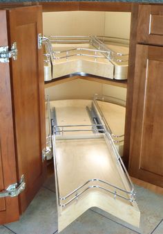 an open cabinet door in a kitchen with wooden cabinets and stainless steel pull out shelves