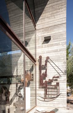 a large metal sculpture sitting on the side of a building next to a glass door