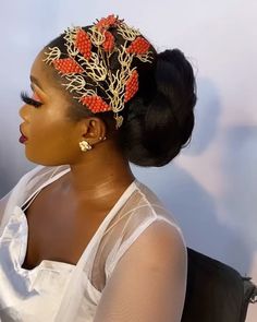 a woman wearing a white top and red beads in her hair