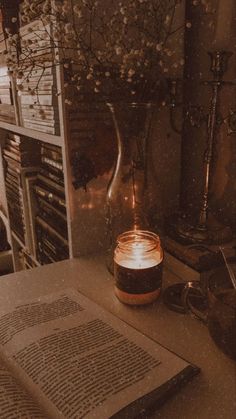 an open book sitting on top of a table next to a vase filled with flowers