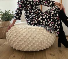 a woman sitting on top of a round ottoman