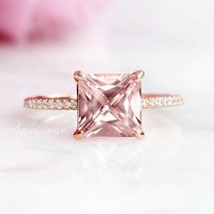 an engagement ring with a pink diamond in the center and white diamonds on the sides