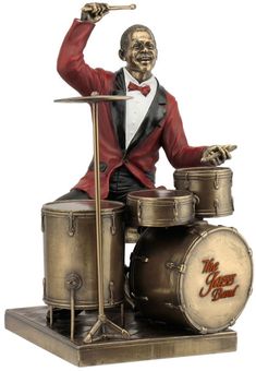 a statue of a man playing drums on top of a metal drum set with a red jacket and bow tie