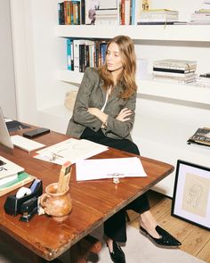 a woman sitting at a desk in front of a book shelf with books on it