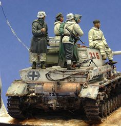 some toy soldiers are sitting on top of a tank with another figure in the background