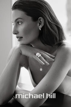 a black and white photo of a woman with her hands on her chest, looking off to the side