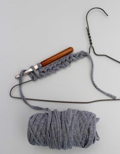 a crochet hook and yarn on a white surface with a wooden handle next to it